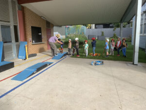 Kids learning to ride a skateboard over skate ramps.