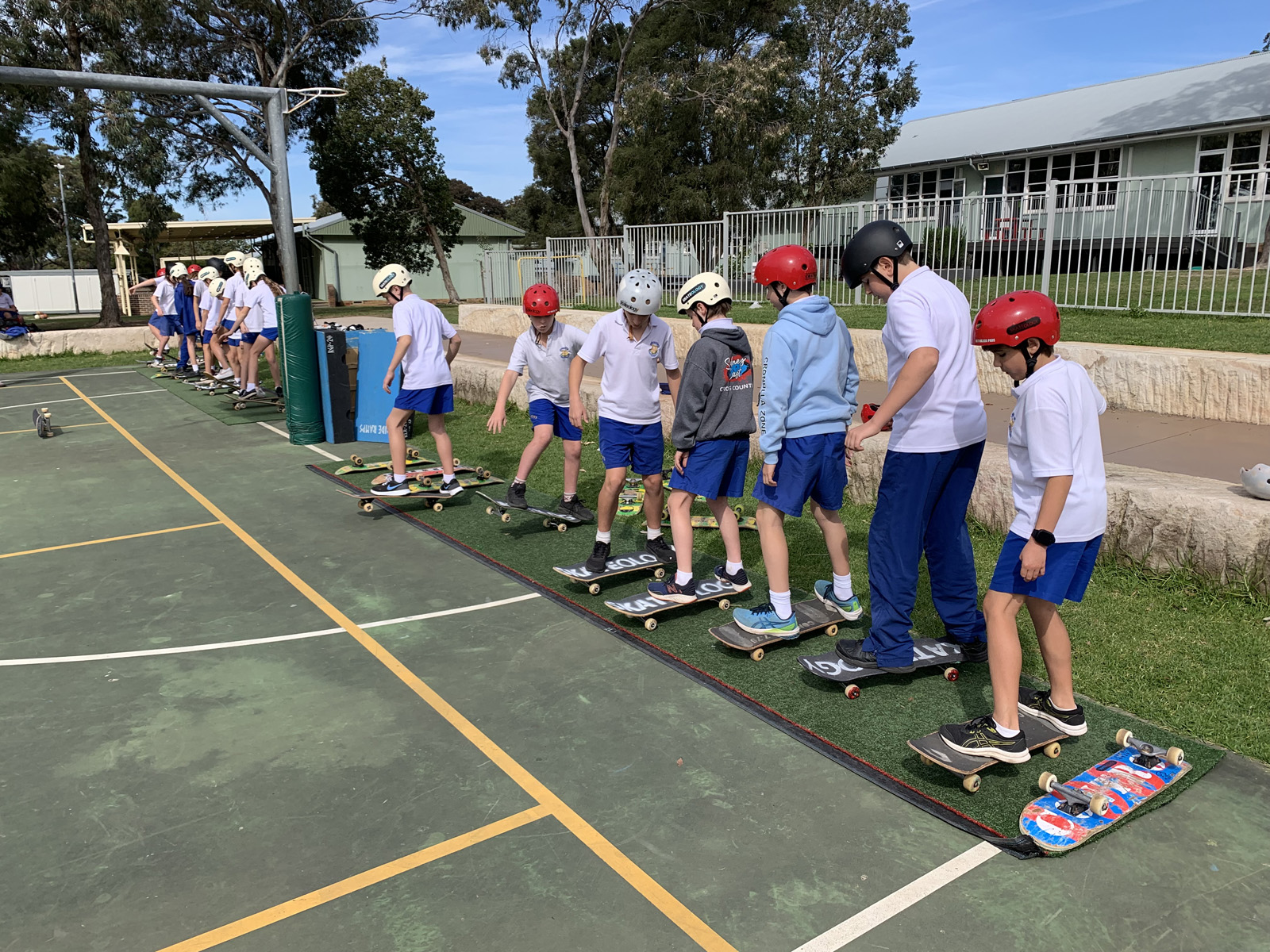 Kids line up on skateboards at school.